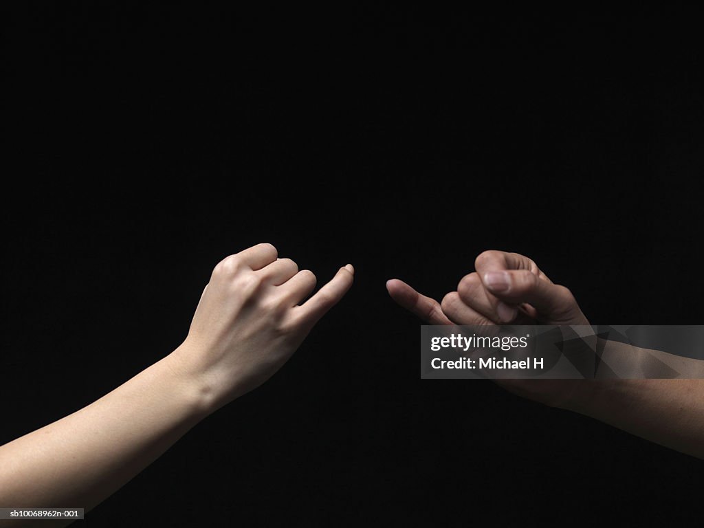 Man and woman pinky-swearing, close-up of hands