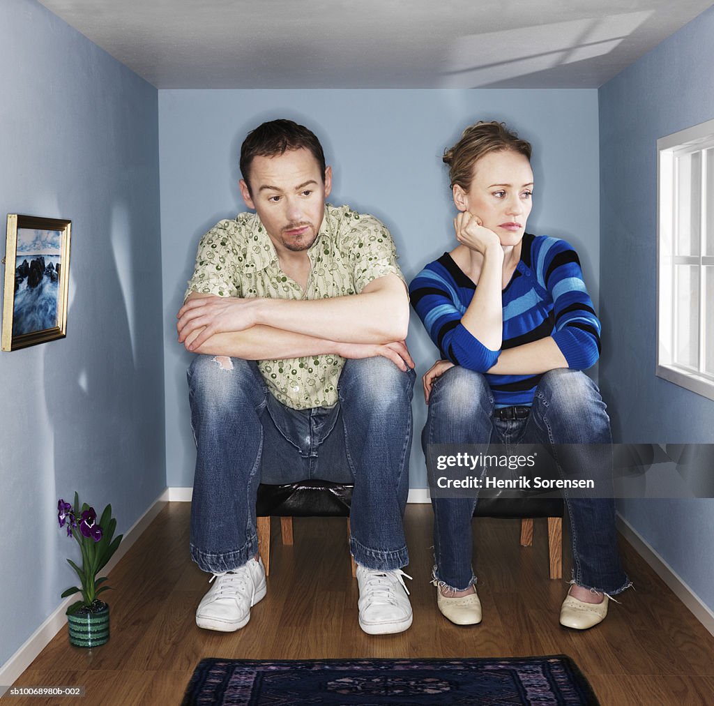 Couple sitting in mall living room, looking depressed