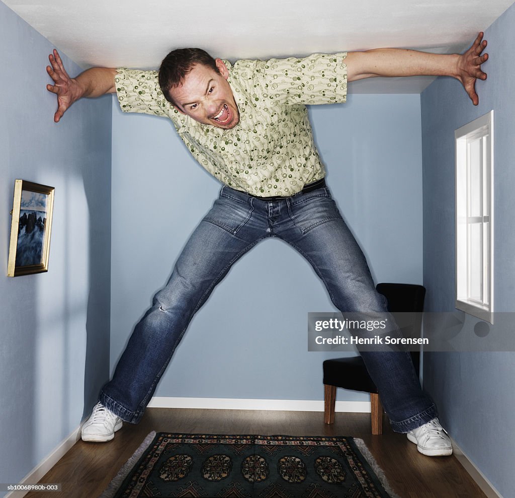 Man standing and screaming in small living room, portrait