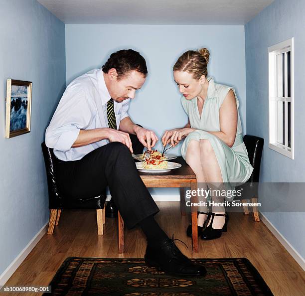 couple eating dinner in small dining room - large man stock-fotos und bilder