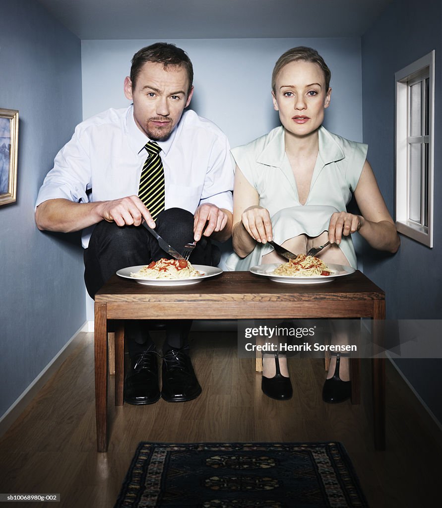Couple eating dinner in small dining room, portrait