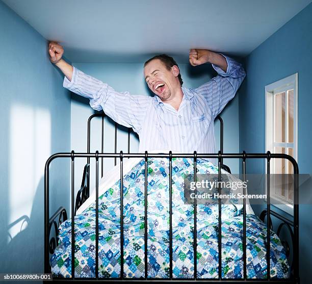 man yawning and stretching in small bed room. - large room stock pictures, royalty-free photos & images