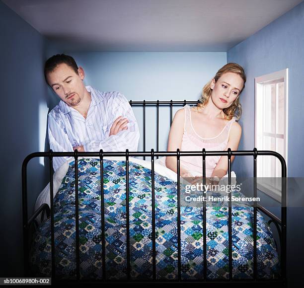 couple sitting in small bed room, looking depressed - small room stock pictures, royalty-free photos & images