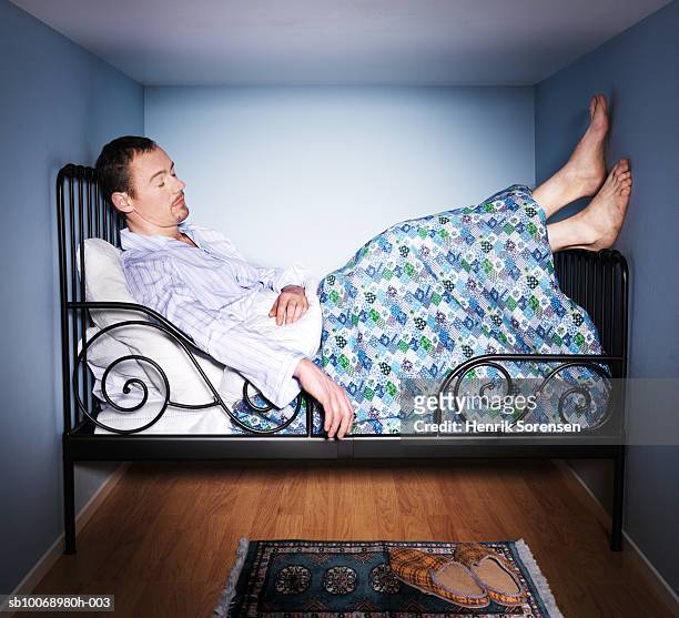 man sleeping in small bed room, side view - small stockfoto's en -beelden