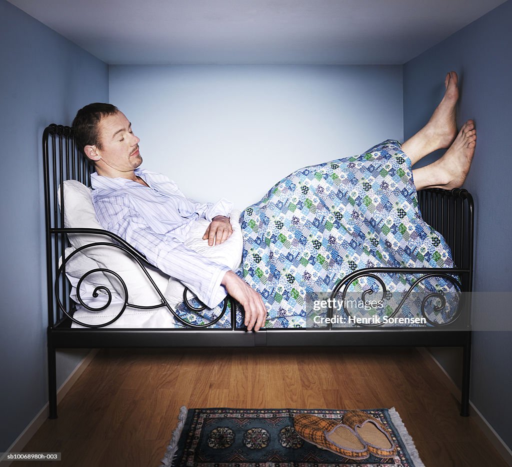 Man sleeping in small bed room, side view