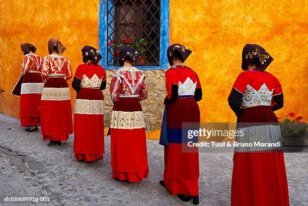 italy, sardinia, fonni, young women in traditional costumes in row, rear view - abiti da cerimonia foto e immagini stock