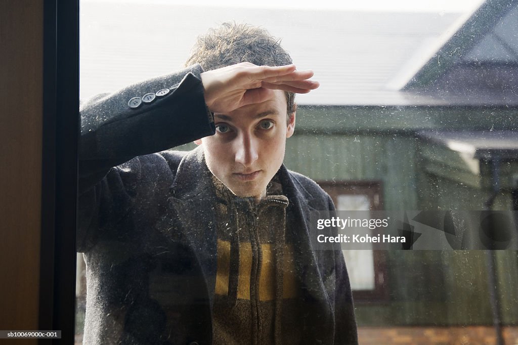 Young man peeking trough window, portrait