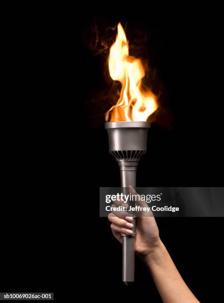 woman holding silver torch, on black background - torch stock-fotos und bilder