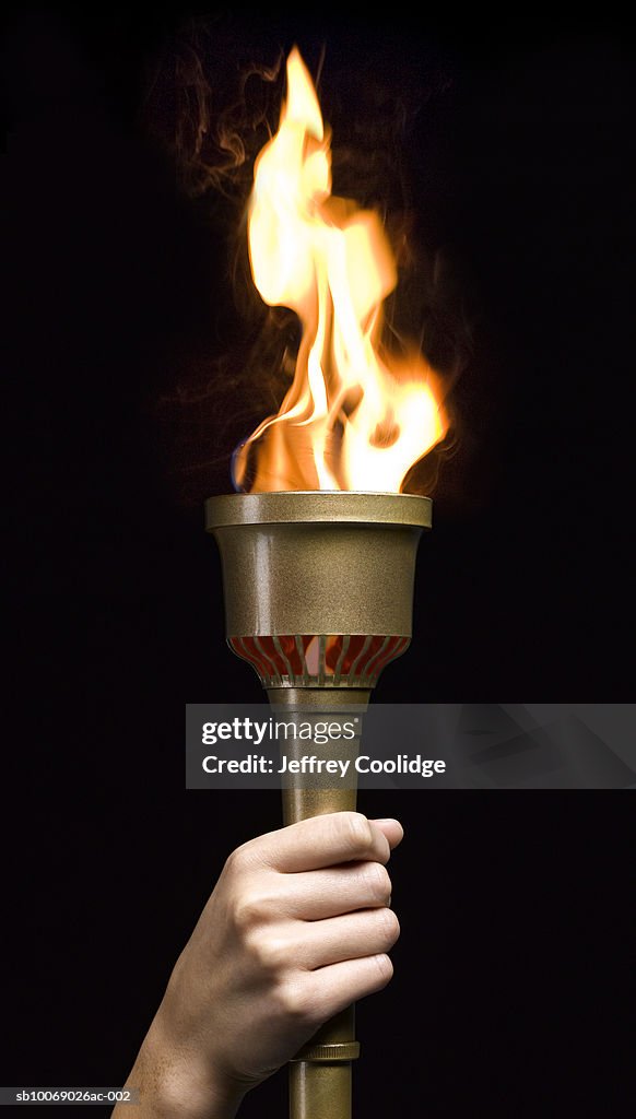 Woman holding gold torch, on black background