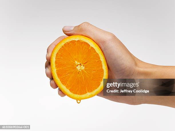 woman's hand squeezing orange slice, studio shot - spremere foto e immagini stock