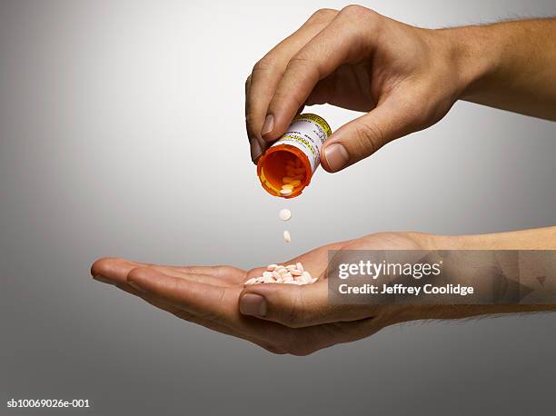 man pouring prescription pills into hand, close-up, studio shot - hand pouring stock pictures, royalty-free photos & images