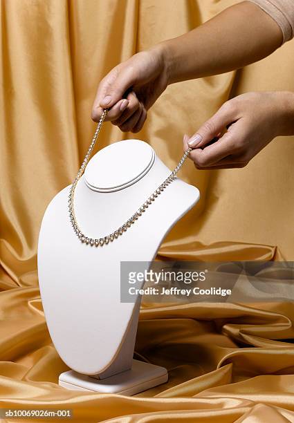 woman placing diamond necklace on jewelry stand, studio shot - diamond necklace stock pictures, royalty-free photos & images