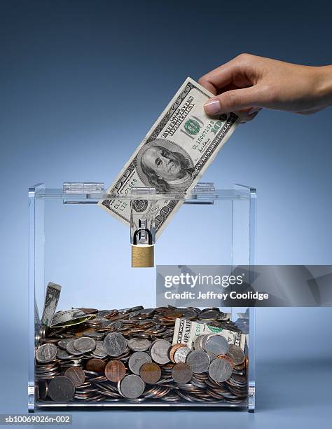 woman's hand placing dollar bill into collection box filled with money, studio shot - money donation stock pictures, royalty-free photos & images