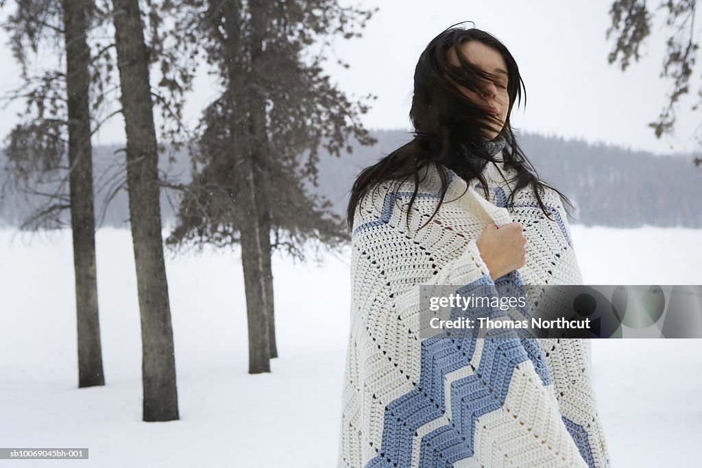 Young woman standing in snow, eyes closed