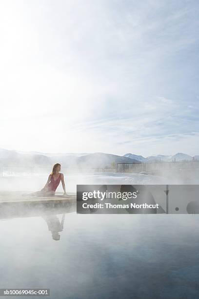 junge frau sitzt am pool - hot springs stock-fotos und bilder