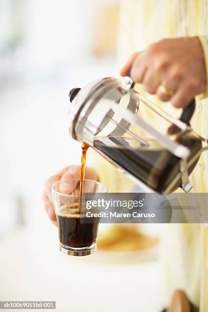 man pouring coffee from cafetiere in to mug, close-up, mid section - coffee plunger stock-fotos und bilder