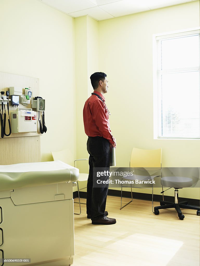 Doctor standing in exam room looking out window