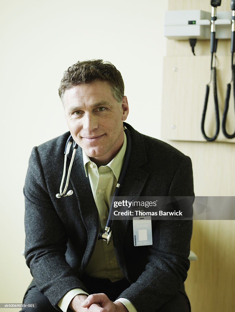 Male doctor in exam room, smiling, portrait, close-up