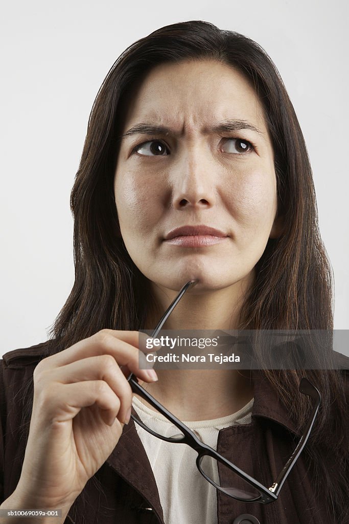 Studio shot of woman holding glasses and looking up