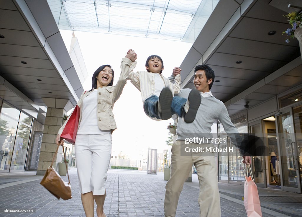 Parents lifting up son (6-7) in shopping mall