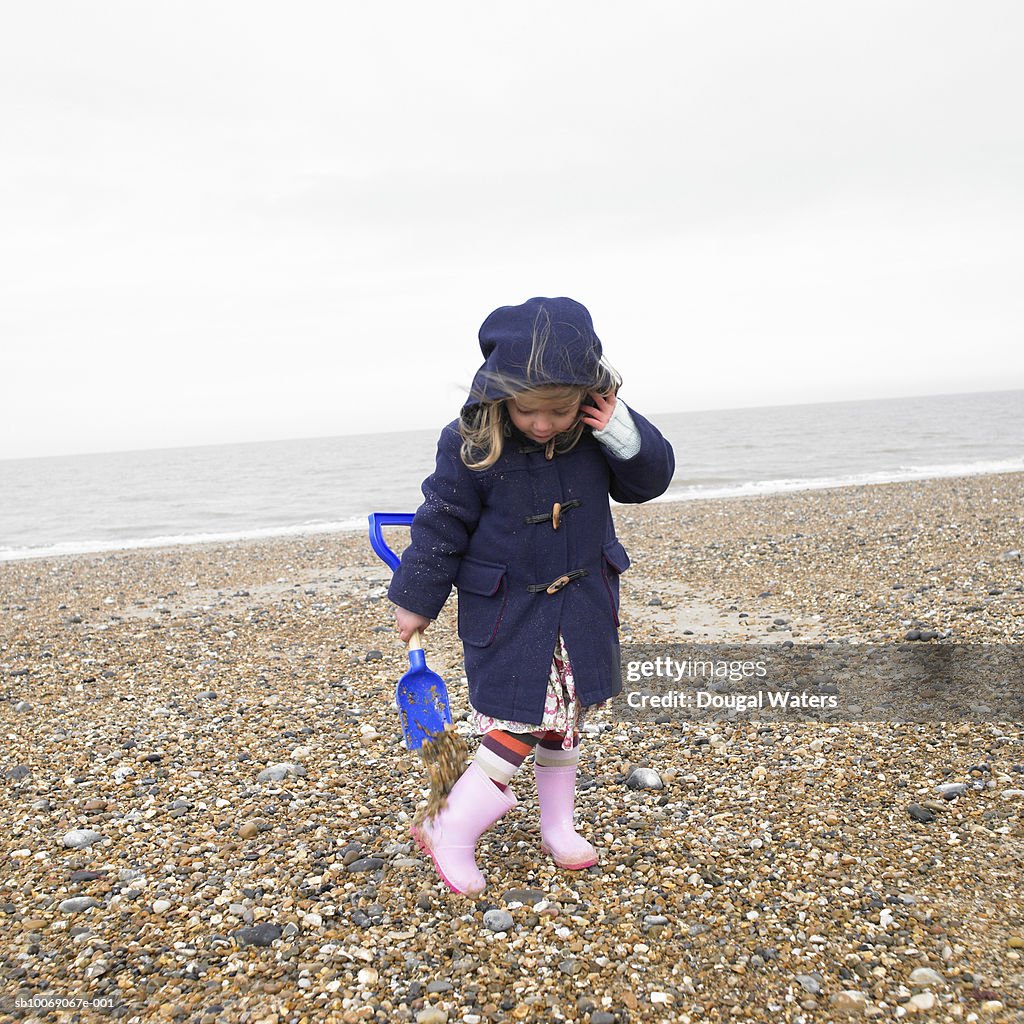 Girl (2-3) playing on beach with spade