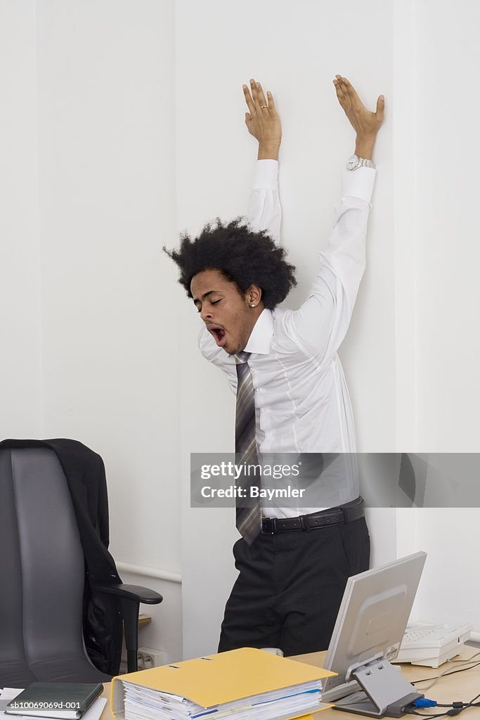 Businessman stretching in office (Digital Composite)