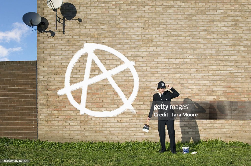 Policeman painting graffiti on wall