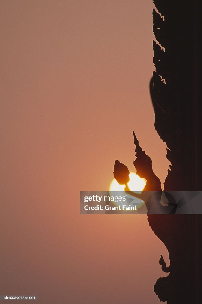 Thailand, Bangkok, silhouette of figure on temple wall at sunset