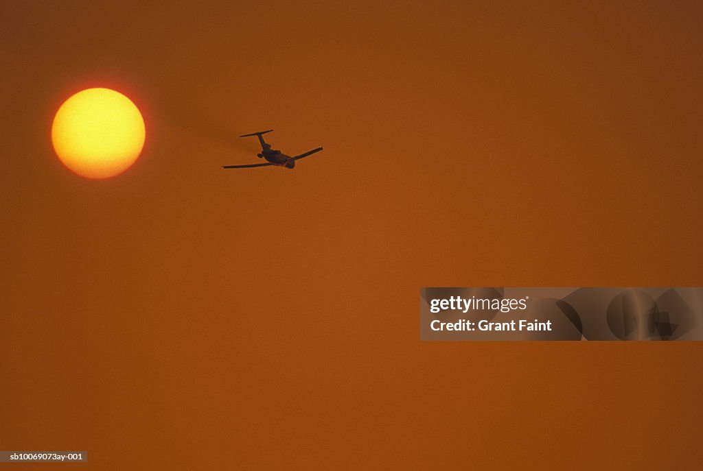 Airplane against sky at sunset