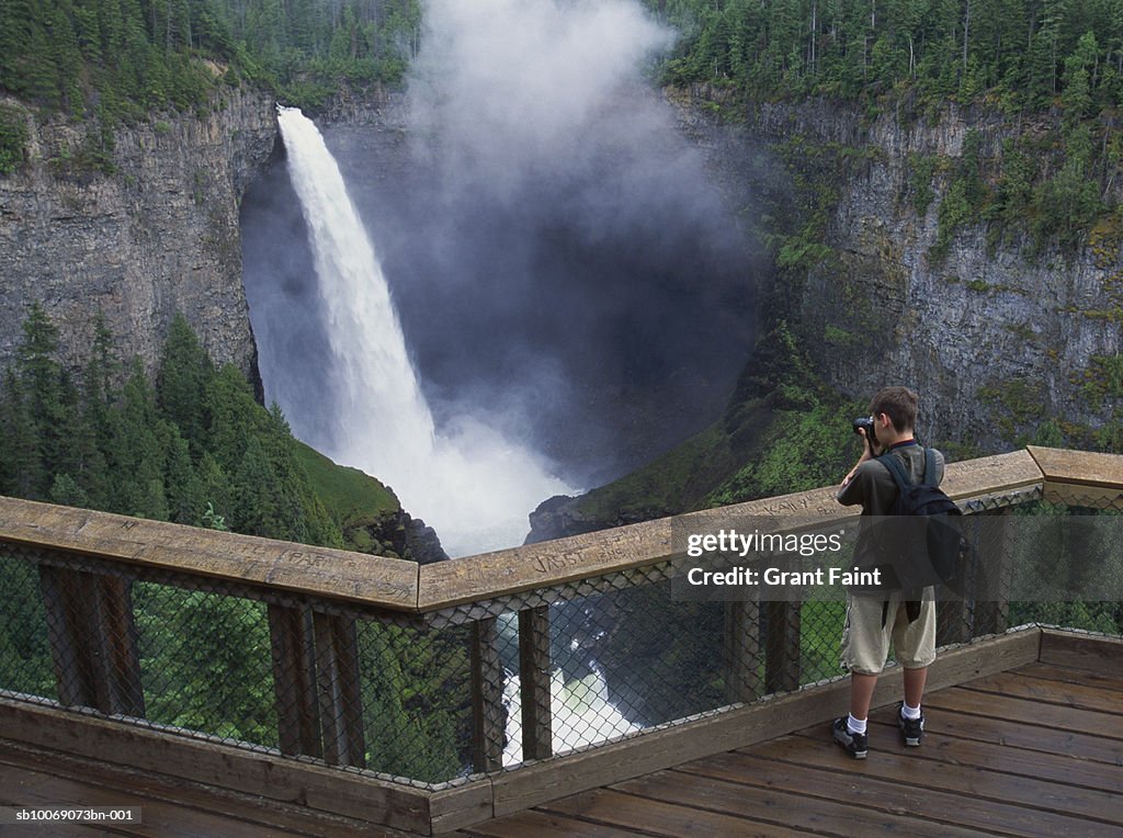 Canada, British Columbia, young man photographing Helmechen falls, rear view