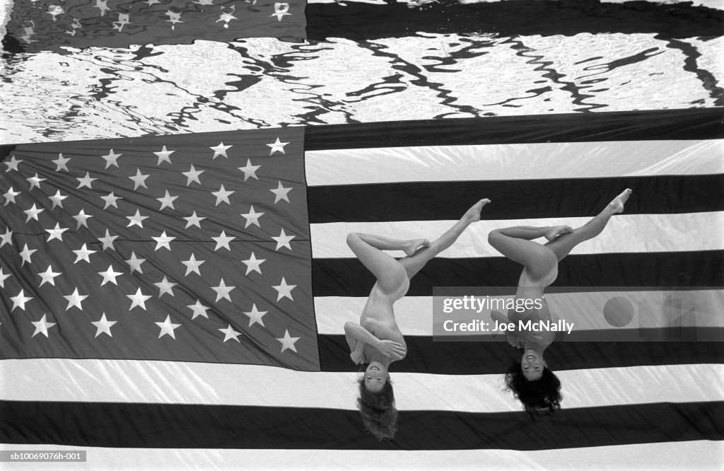 USA, Georgia, Atlanta, naked Olympic synchronized swimmers on American flag, directly above, portrait