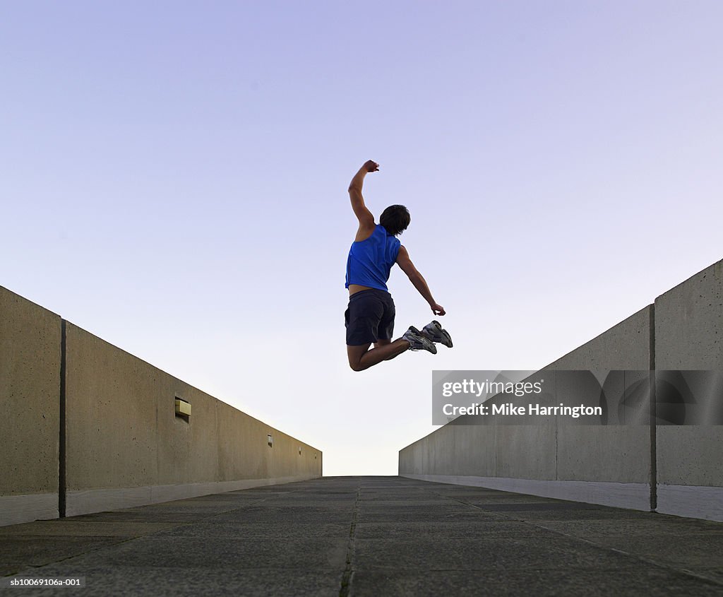 Man jumping in urban setting, rear view