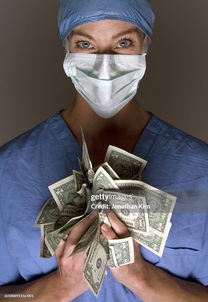 Female doctor holding US dollars, portrait