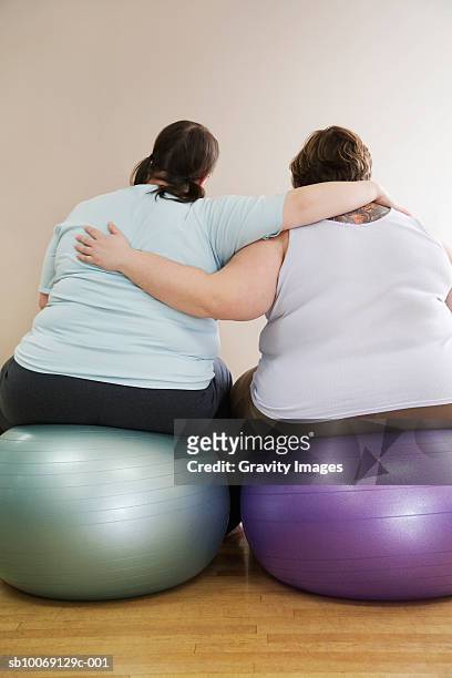 two overweight women sitting on fitness ball, rear view - kräftig gebaut stock-fotos und bilder