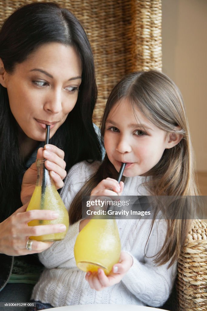 Girl (8-9) and mother drinking juice