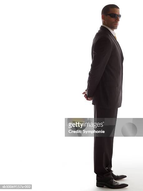 man in full suit standing with his hands back, side view - security guard foto e immagini stock