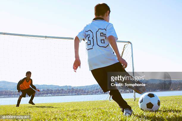 soccer boy taking shot at goal, goalkeeper watching - rematar �� baliza imagens e fotografias de stock