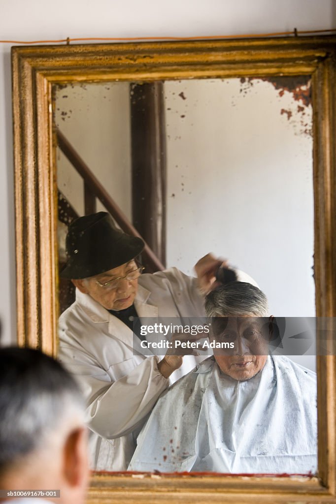 Barber cutting senior man's hair