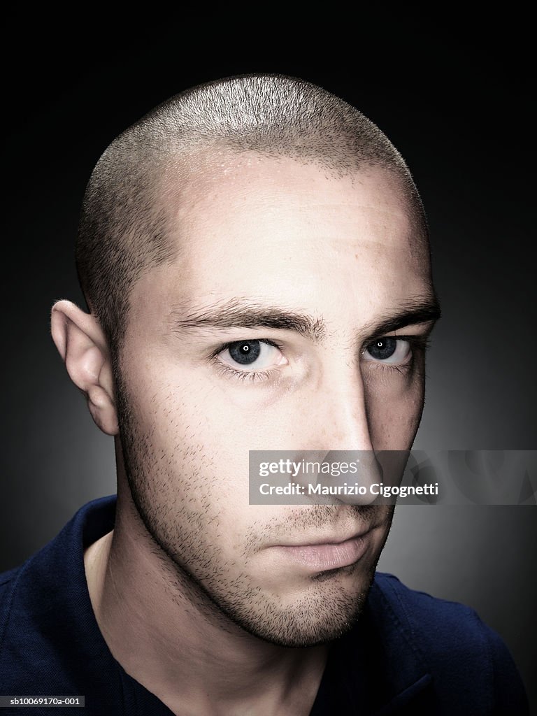 Young man with shaved head, portrait, studio shot