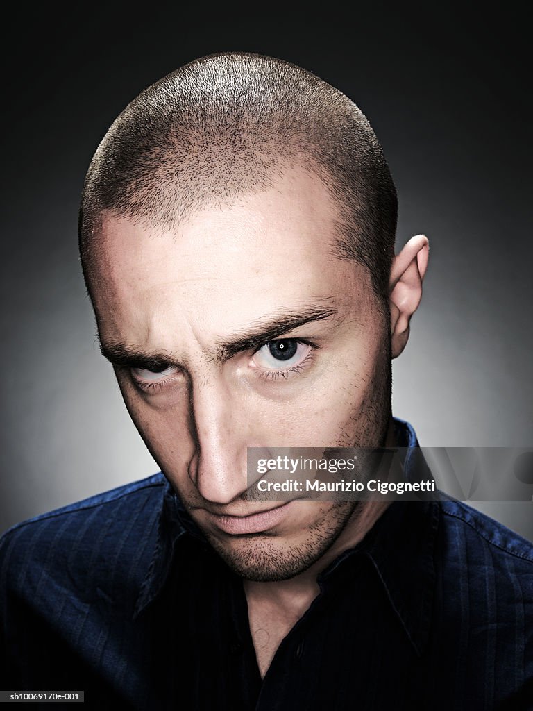 Young man with shaved head, portrait, studio shot