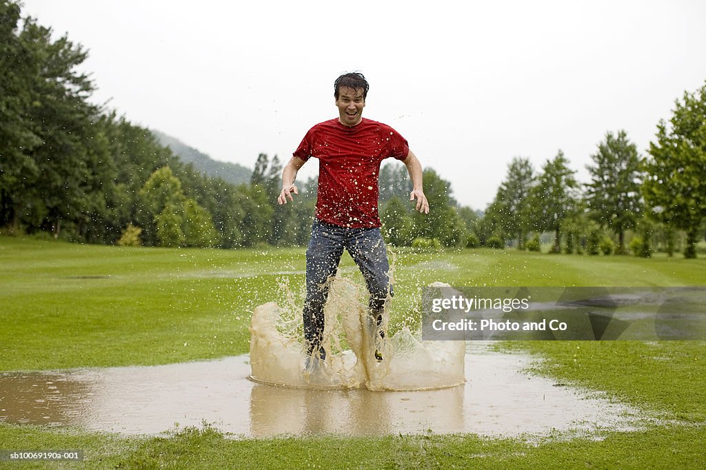 Man jumping in puddle on golf course