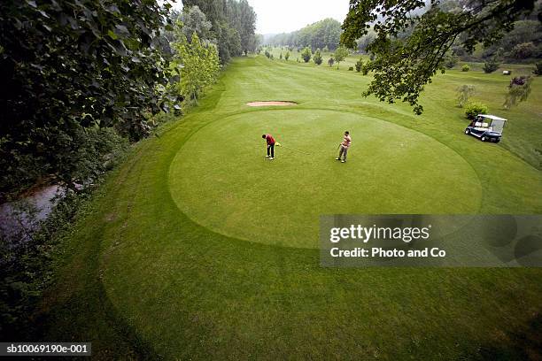 france, dordogne, two golfers on green at golf course, elevated view - putting green stock-fotos und bilder