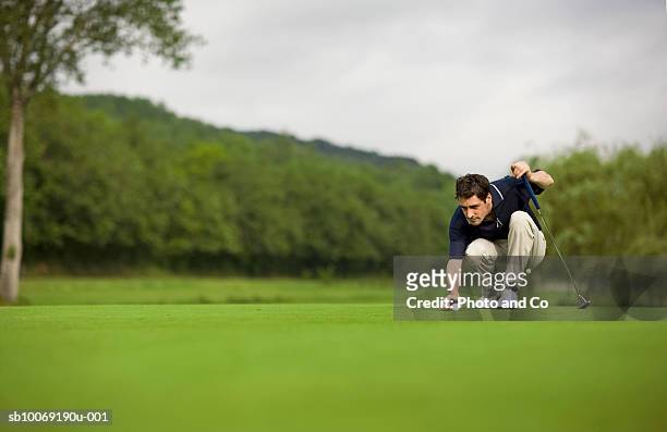 france, dordogne, male golfer lining up shot on green - golf putter stock pictures, royalty-free photos & images