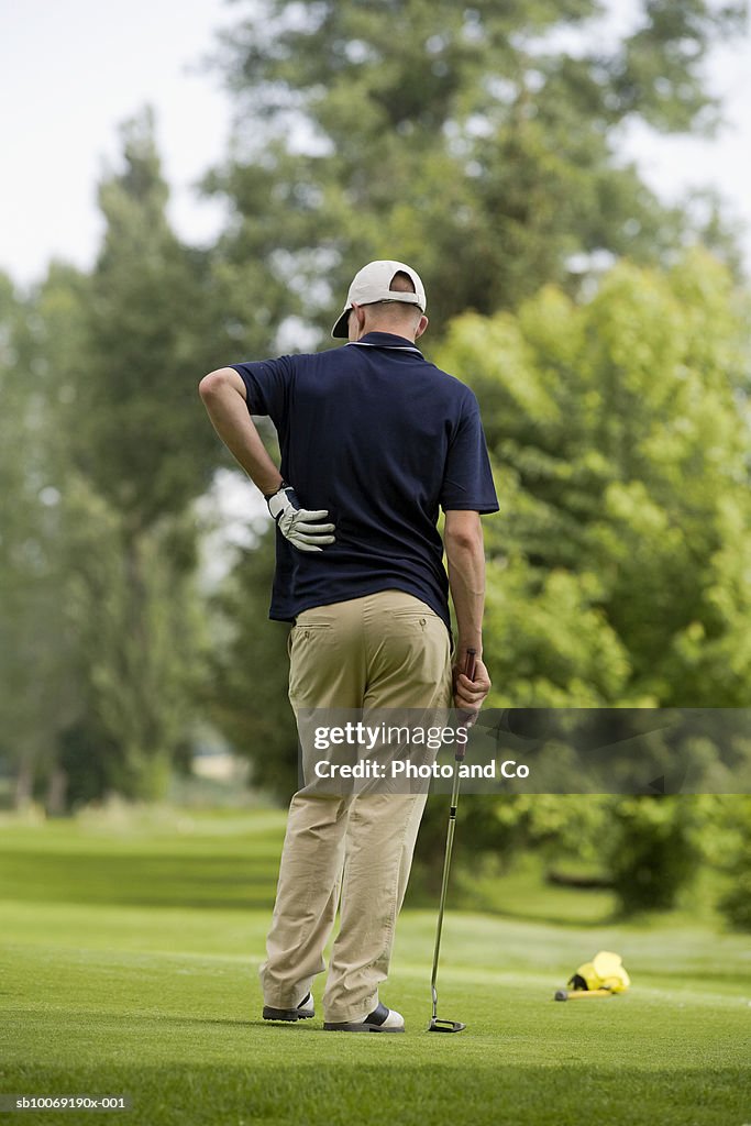 France, Dordogne, male golfer standing on golf course, rear view