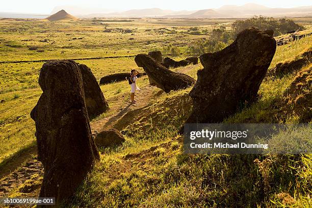 easter island, rano raraka, young woman observing ancient moai statues - easter_island stock pictures, royalty-free photos & images