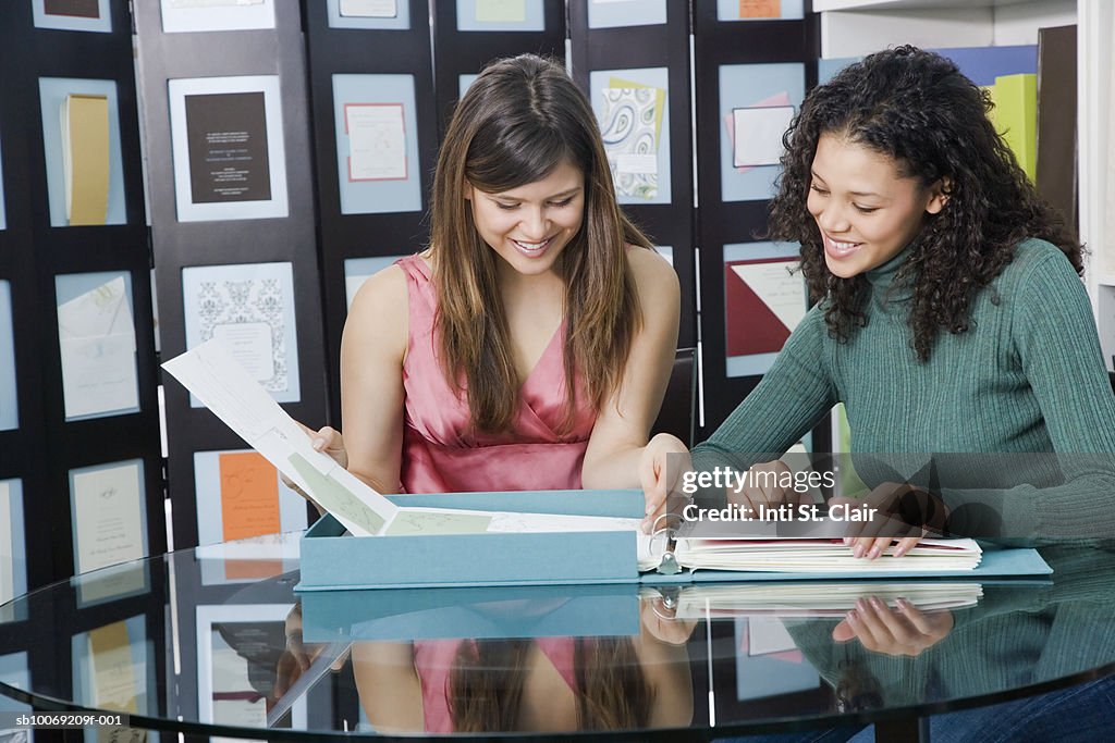 Two young women leafing through folder in shop
