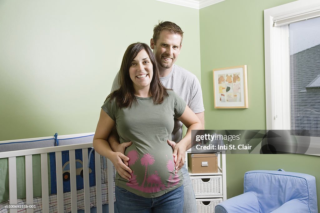 Man and pregnant woman in baby's room, portrait