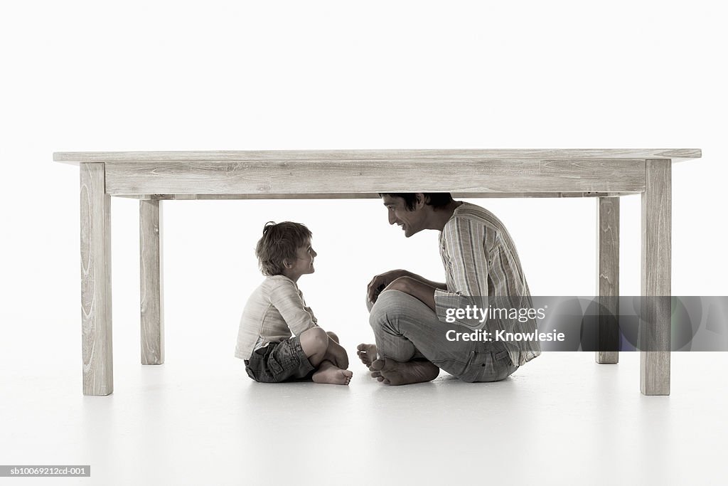 Homem com filho (4-5 anos) sentado na mesa, Fotografia de Estúdio