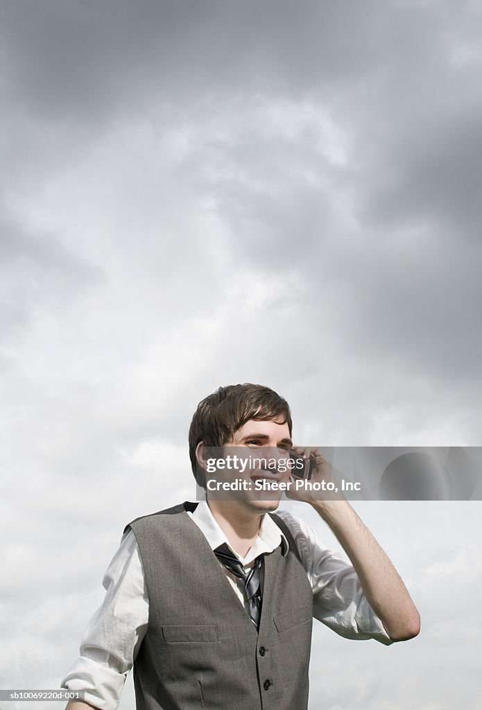 Man using mobile phone, low angle view against sky