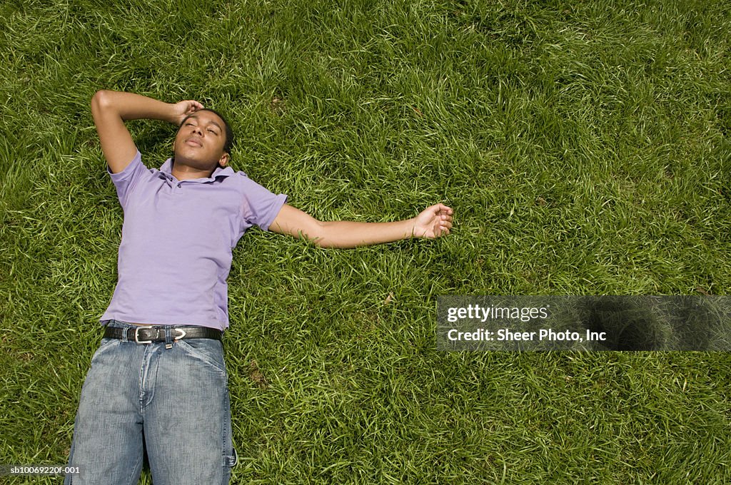 Young man lying in grass, high angle view